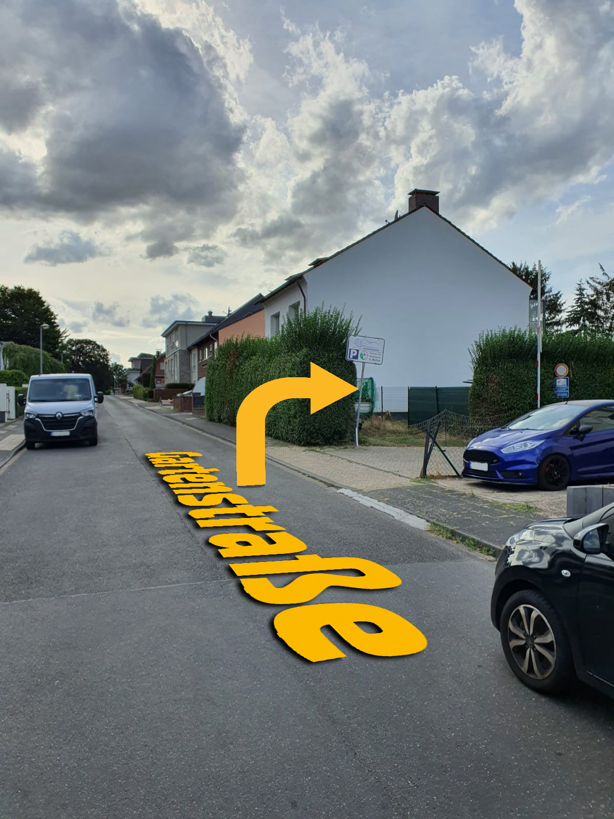 Blick in die Gartenstraße: der gelbe Pfeil zeigt rechts auf die Einfahrt zu den Parkplätzen